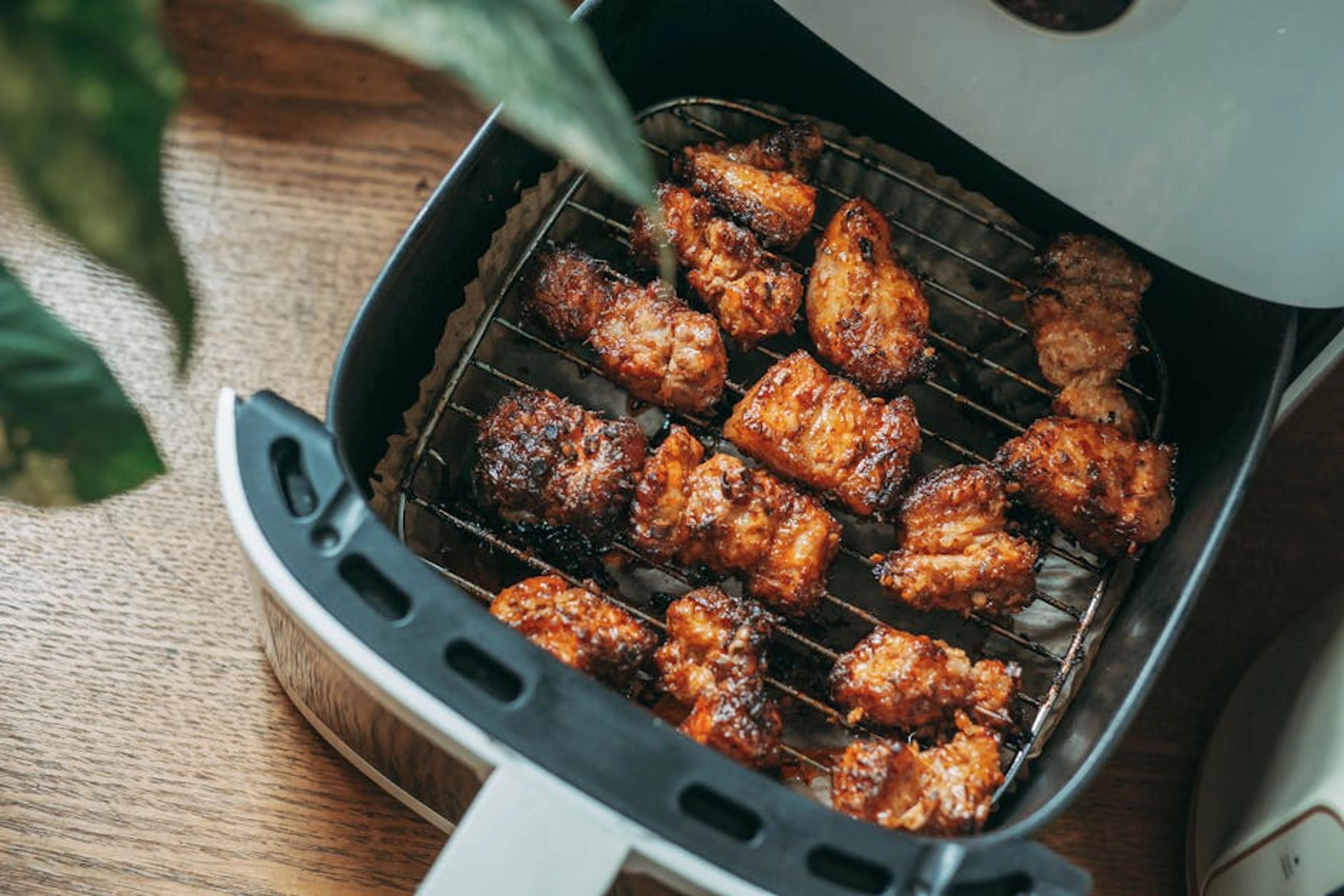 Delicious crispy chicken pieces cooked perfectly in a modern air fryer, ready to serve. Air fryer cooking crispy chicken wings and french fries