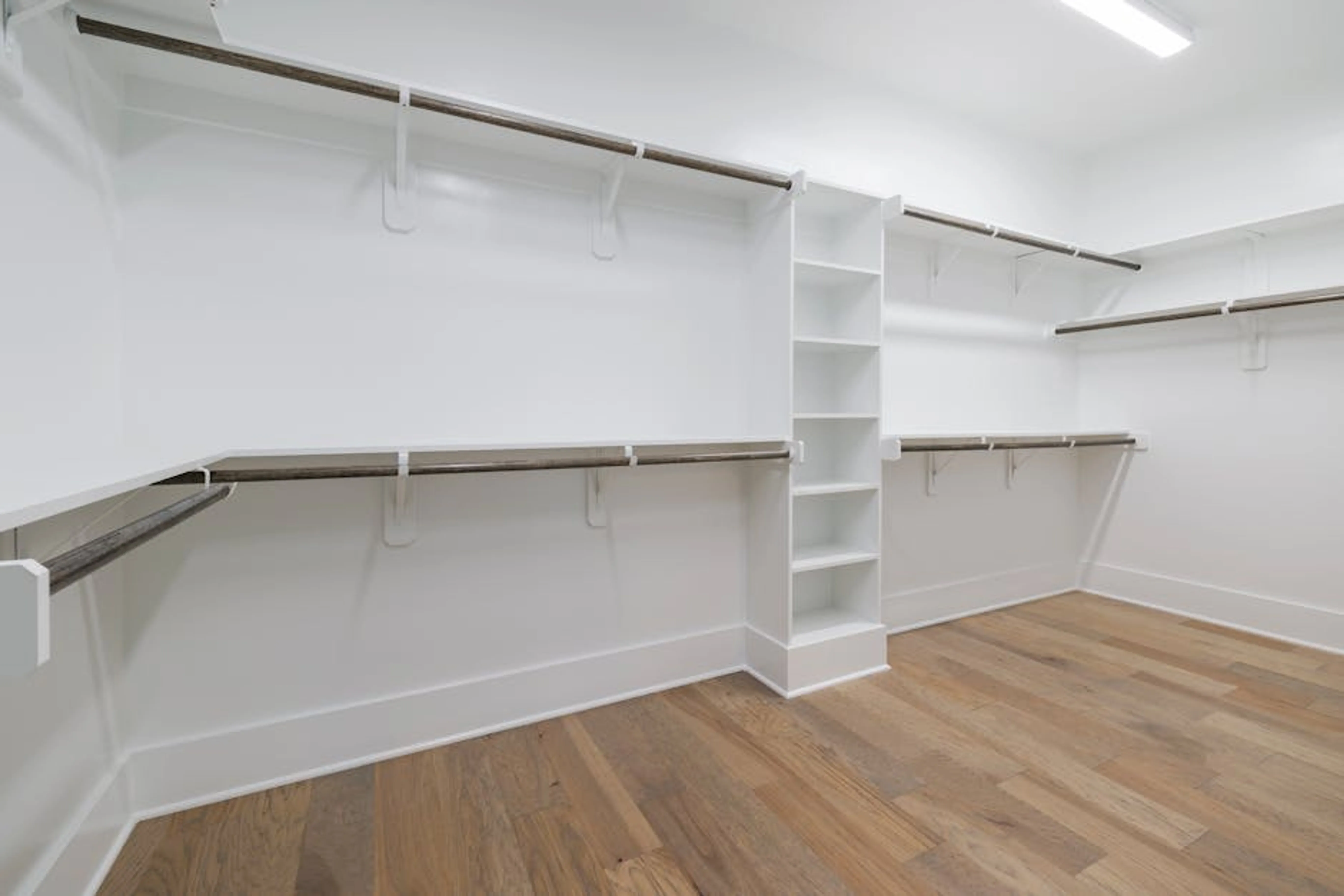Modern empty walk-in closet with wooden flooring and white shelving. Organized pantry with labeled containers and shelves, demonstrating effective home organizing solutions.
