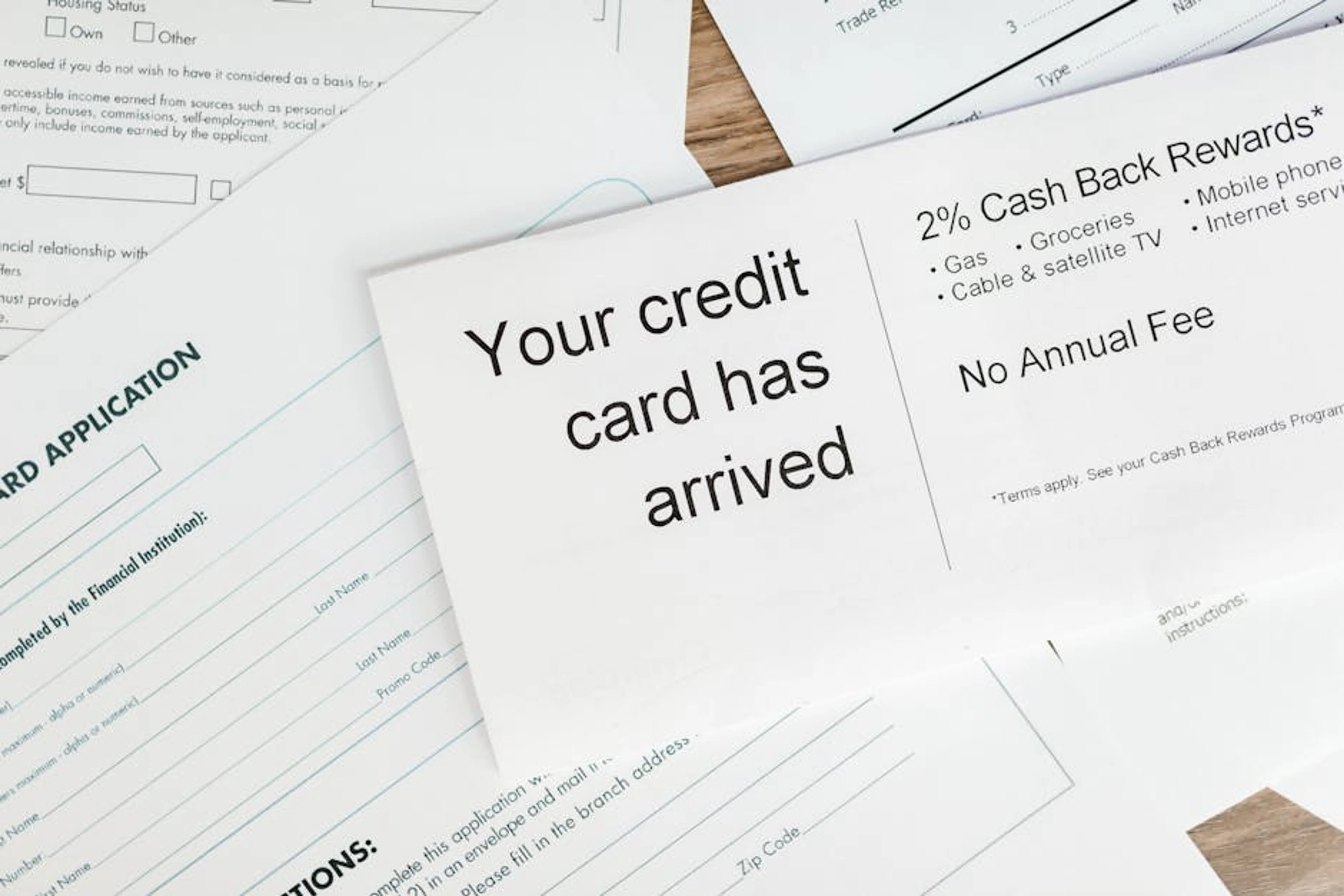 Close-up of a letter announcing the arrival of a credit card amidst financial documents. A person writing down a financial plan to improve their credit score.