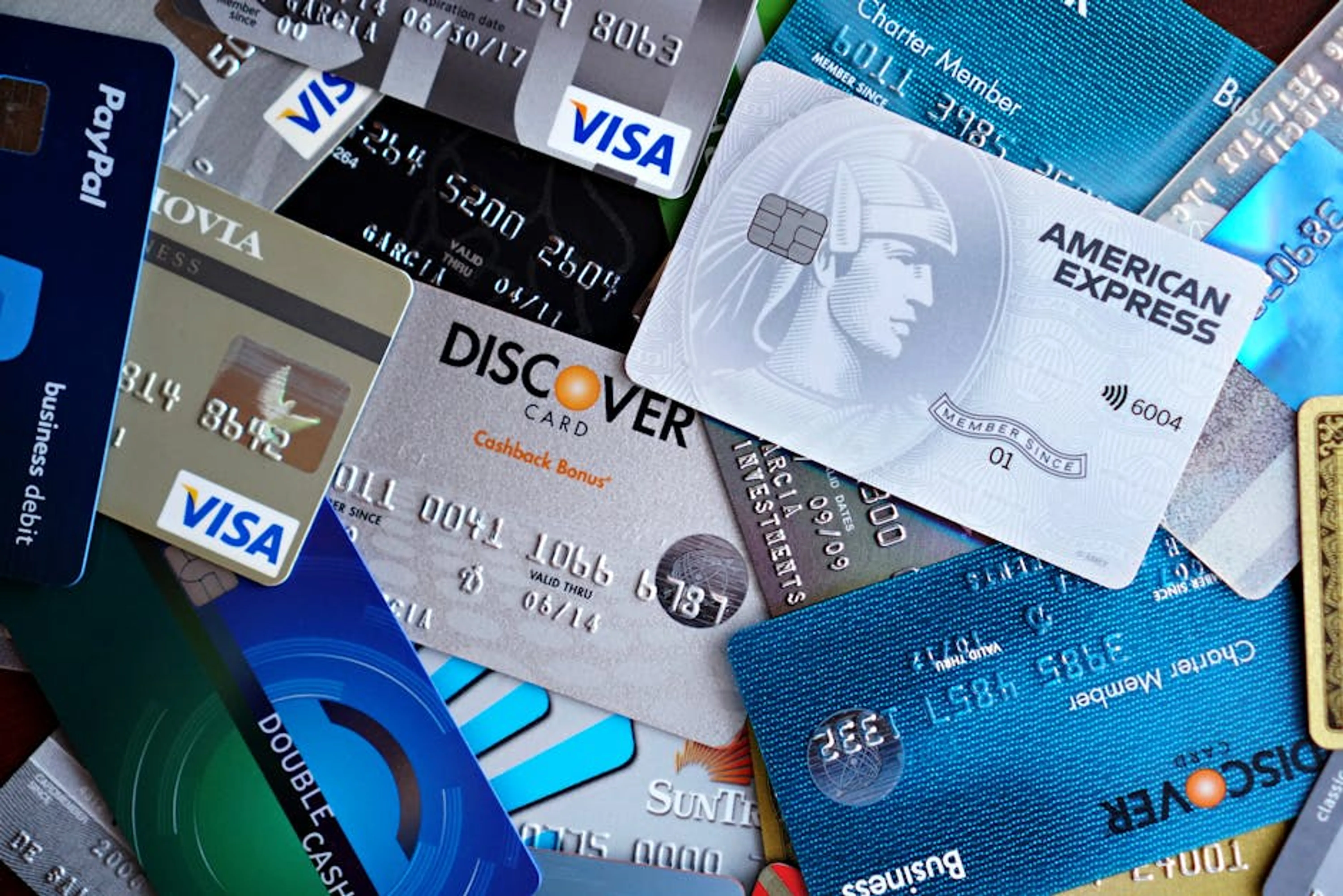 Close-up image of various credit cards including Visa, Mastercard, and American Express. Debt Snowball method showing small debts being paid first, then rolling payments into larger debts.