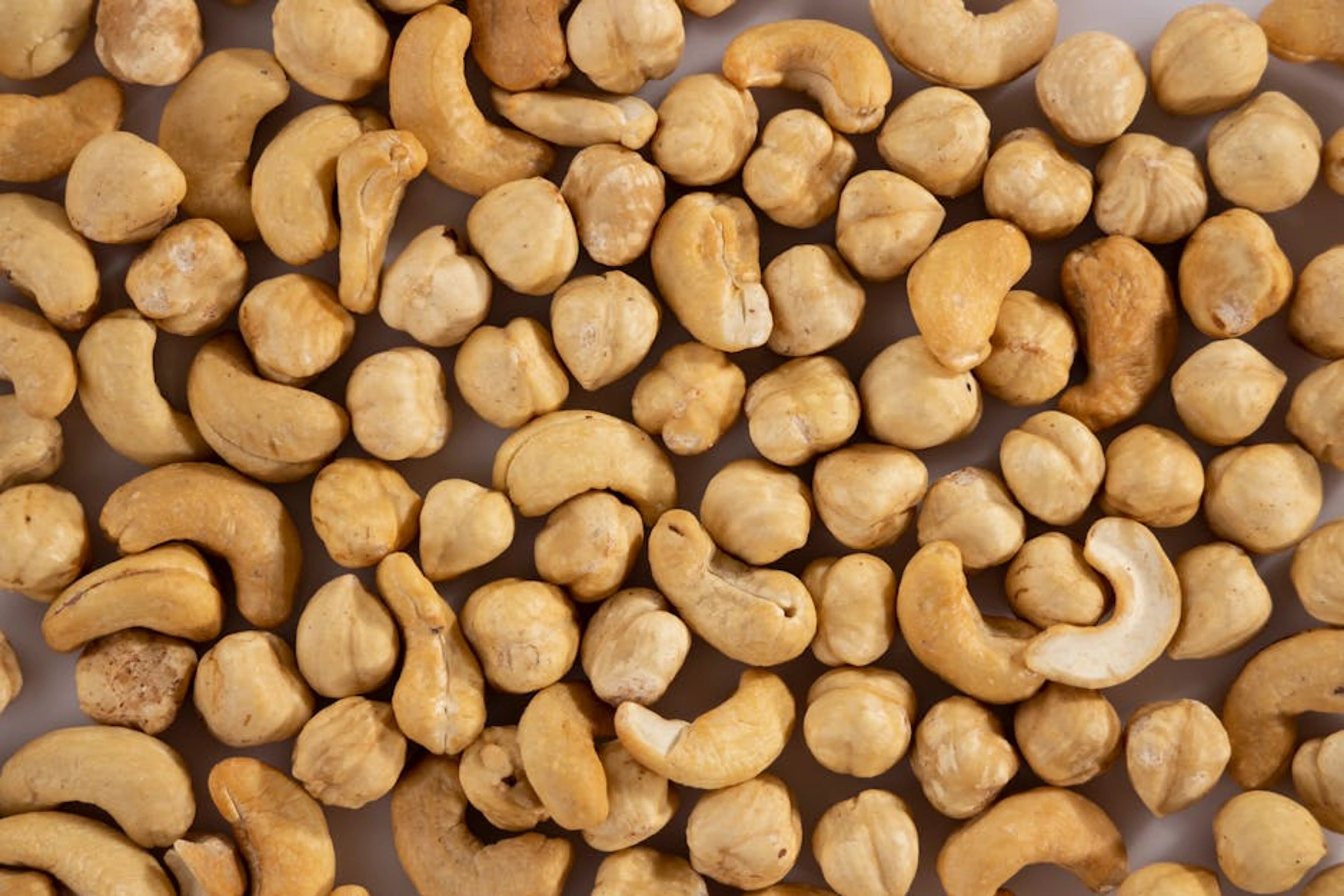 Close-up of assorted cashew and macadamia nuts, showcasing texture and variety. A vibrant bowl of mixed nuts, seeds, and vegetables, representing a hybrid diet.