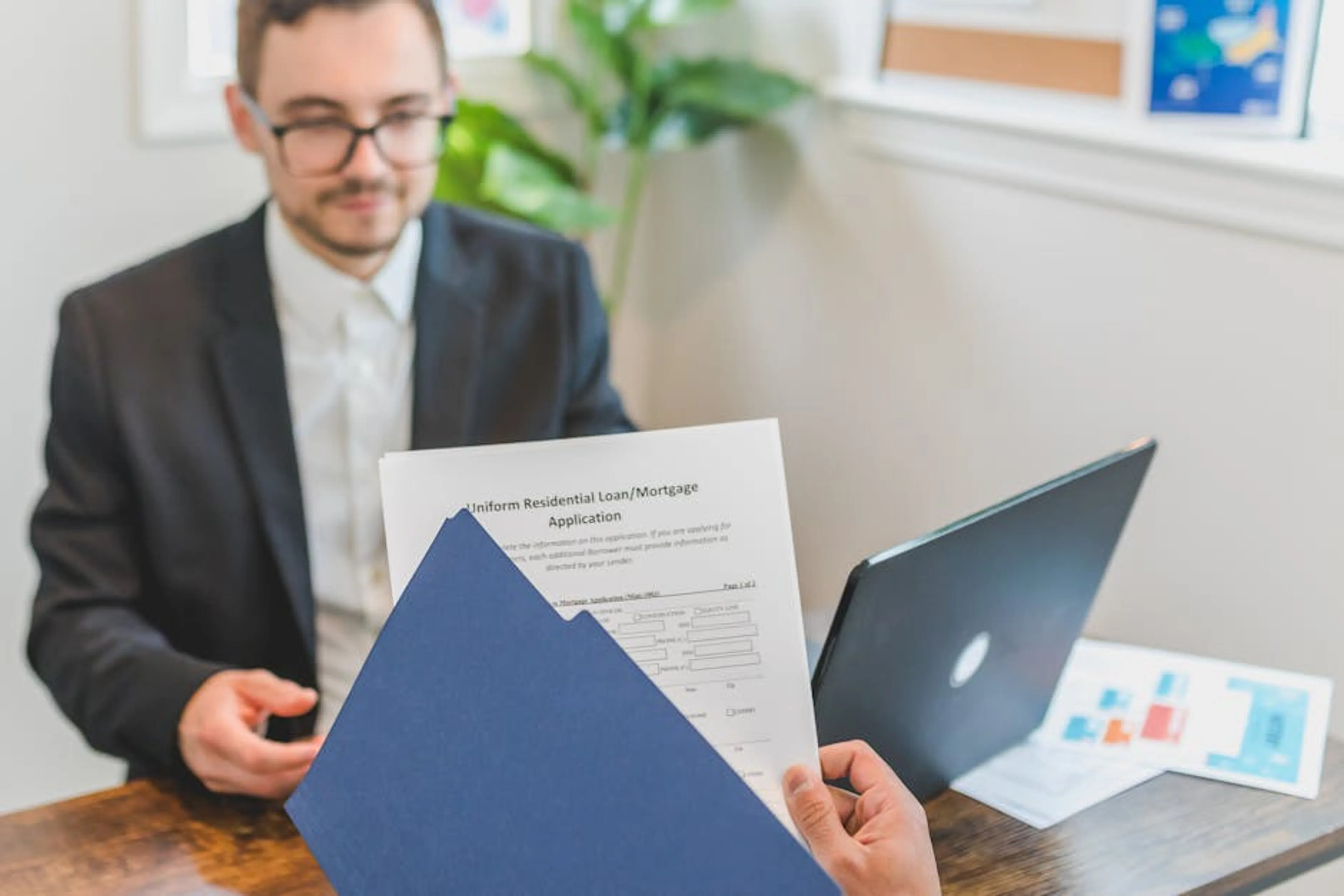 Mortgage broker and client discussing loan application with documents on table. Couple reviewing a mortgage application with a financial advisor