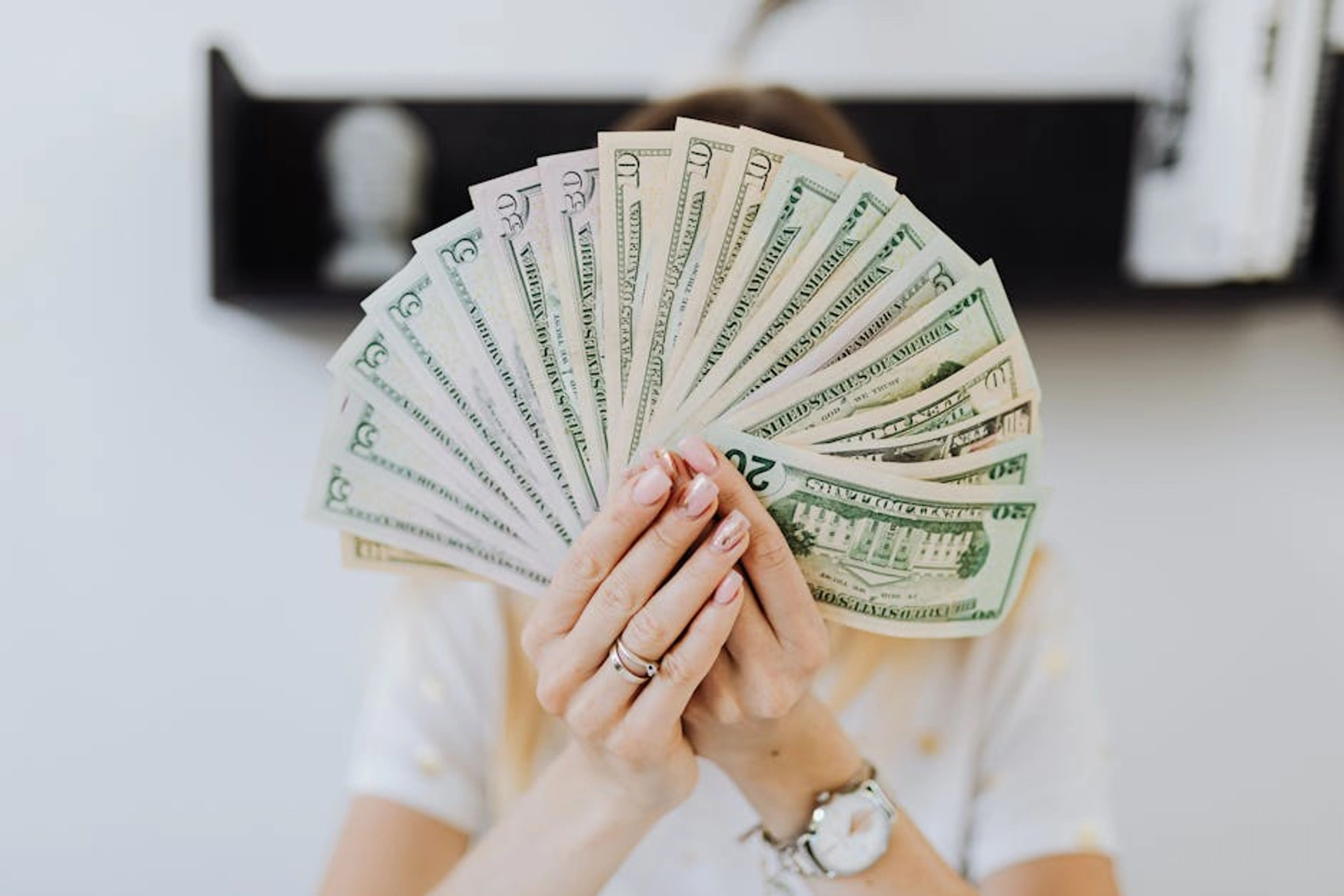 Close-up of hands holding a fan of US dollar bills, showcasing financial abundance. Diverse uses of personal loans illustrated by icons for debt consolidation, home improvement, and emergencies