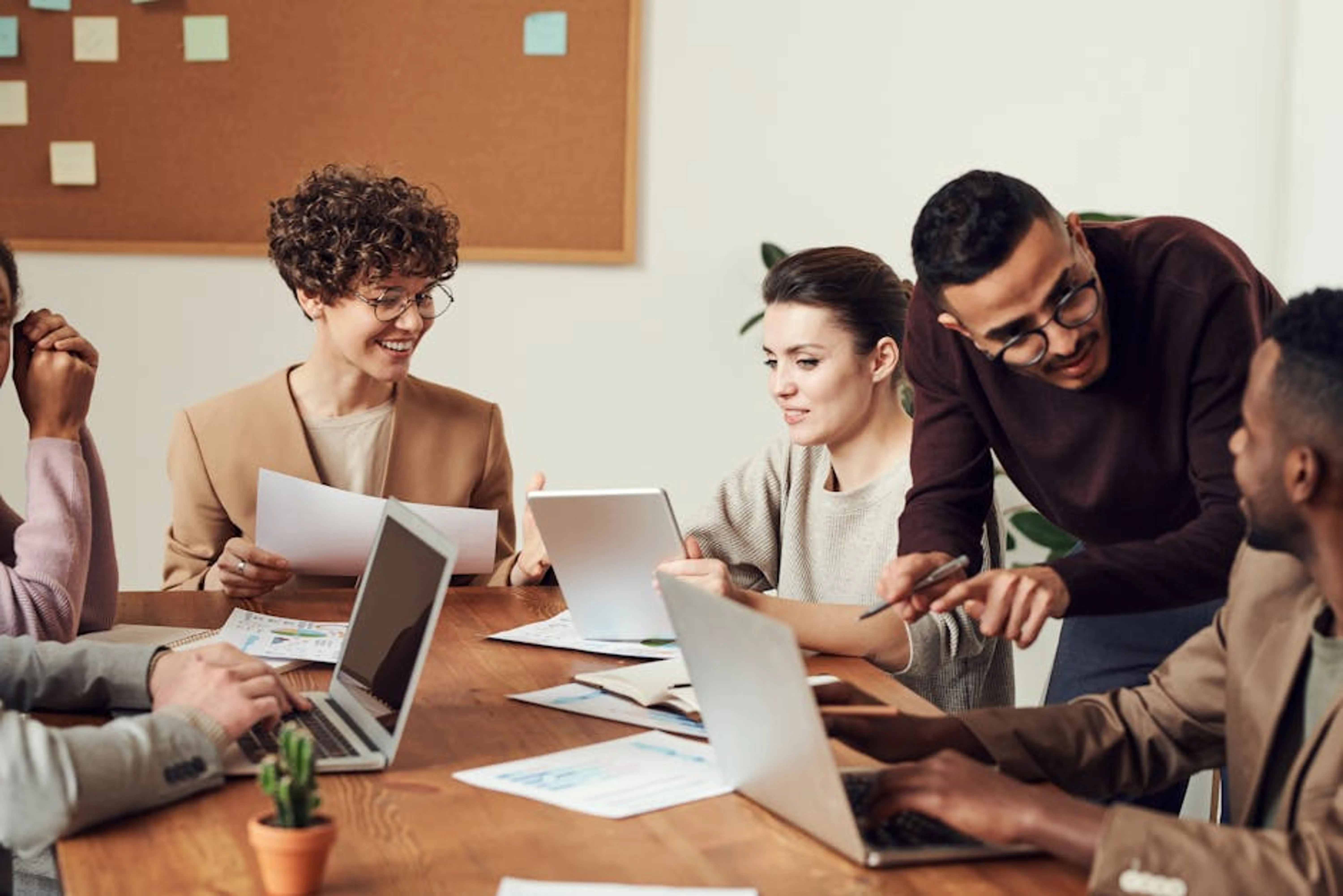 A diverse group of professionals engaged in a collaborative office meeting, sharing ideas and discussing projects. A visual representation of a career path with upward arrows, symbolizing career growth and advancement through certifications.