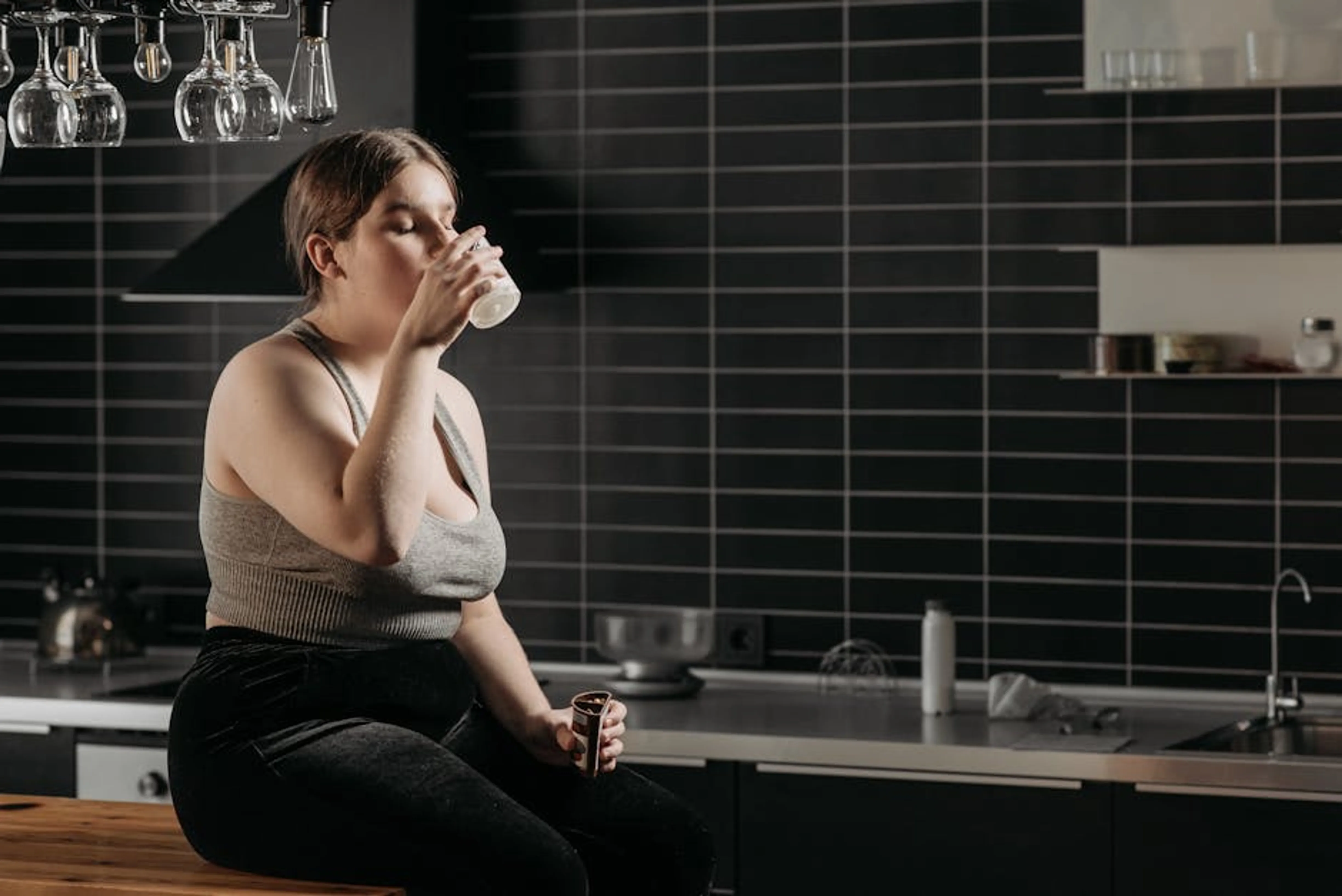 Woman sitting on kitchen counter drinking milk in a modern setting. A person jogging outdoors in daylight, demonstrating healthy daytime activity for better sleep.