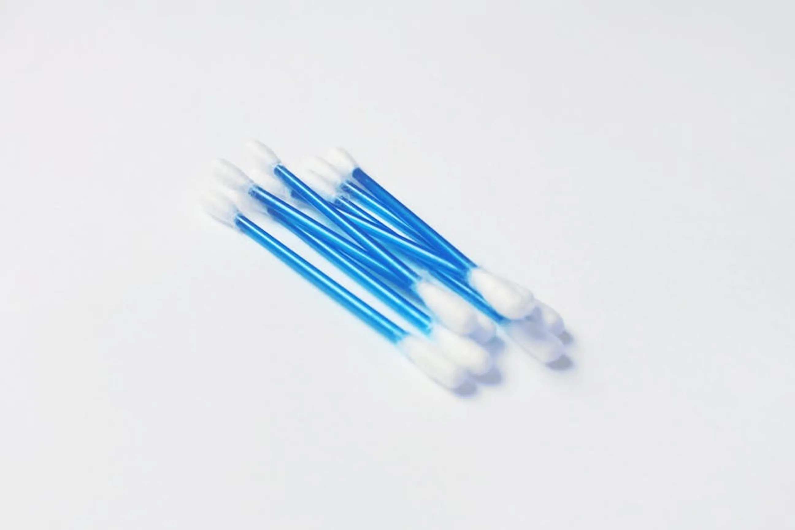 A minimalistic close-up image of blue handled cotton swabs on a white surface. A visual chart summarizing good sleep hygiene practices like dark room, cool temperature, and no screens before bed.