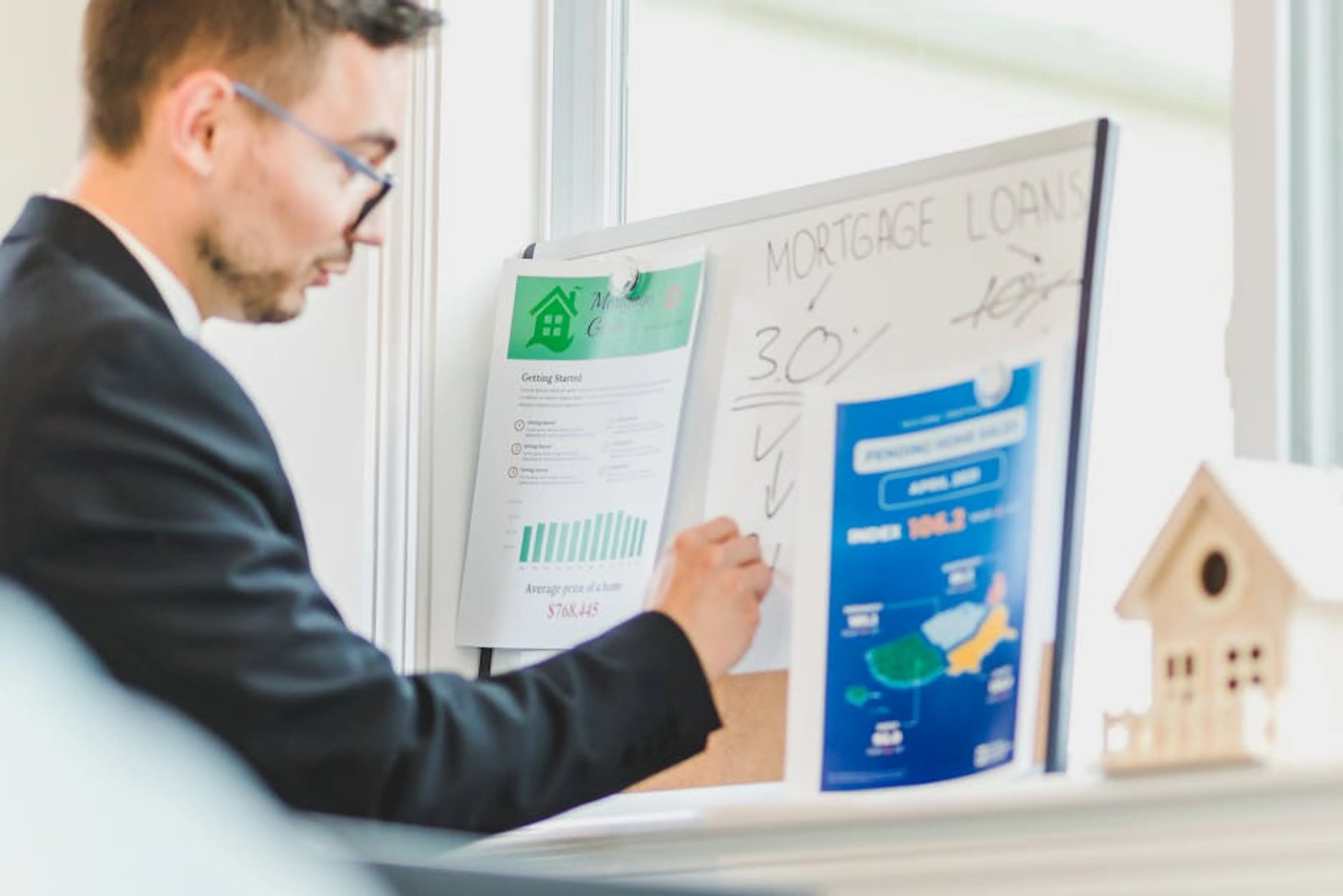 Real estate agent analyzing mortgage loan details on a whiteboard in an office setting. Digital dashboard displaying student loan payment progress