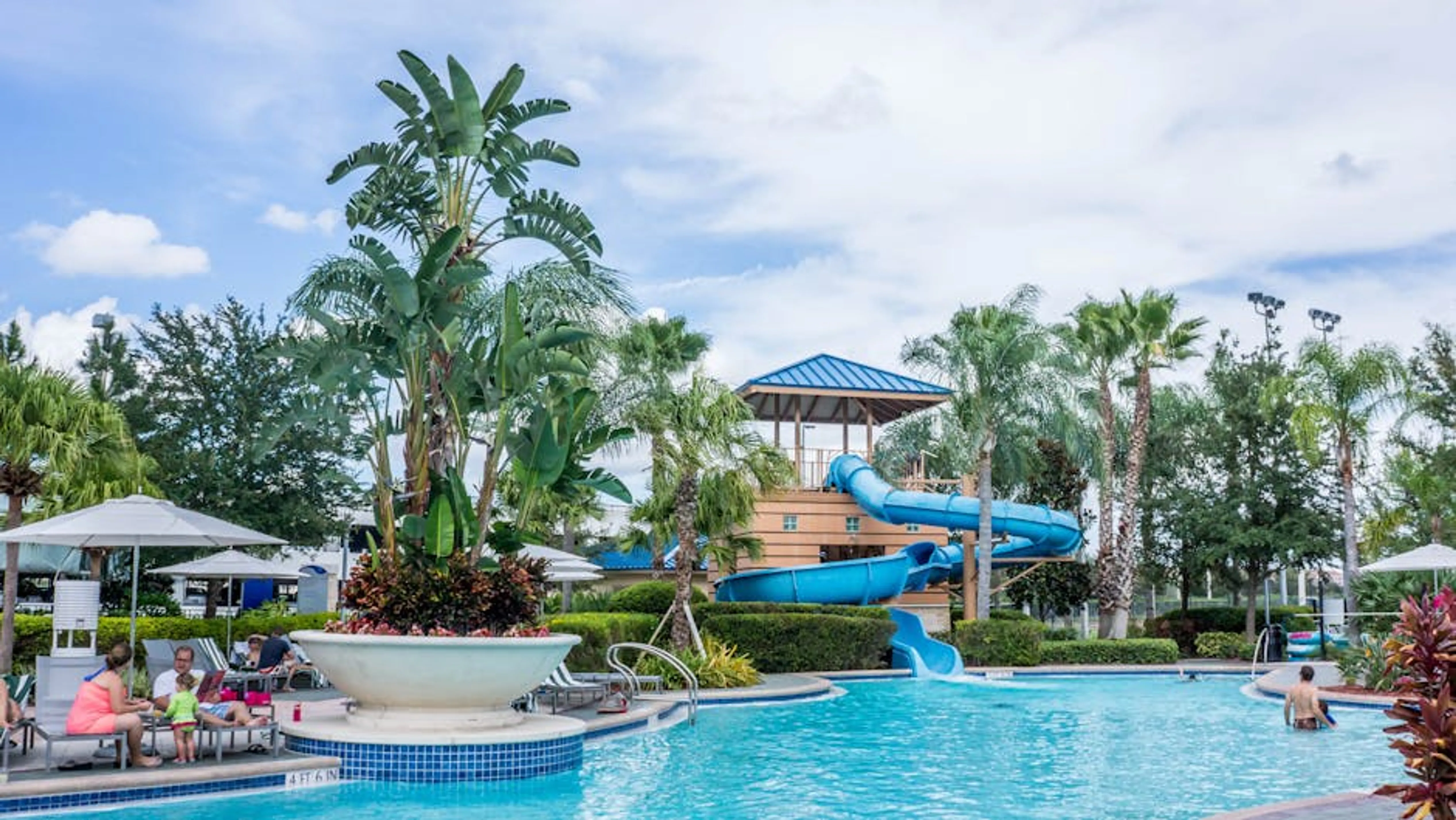Vibrant tropical resort scene featuring a pool, waterslide, and lush palm trees, ideal for summer vacations. Happy family enjoying a luxurious beach vacation together