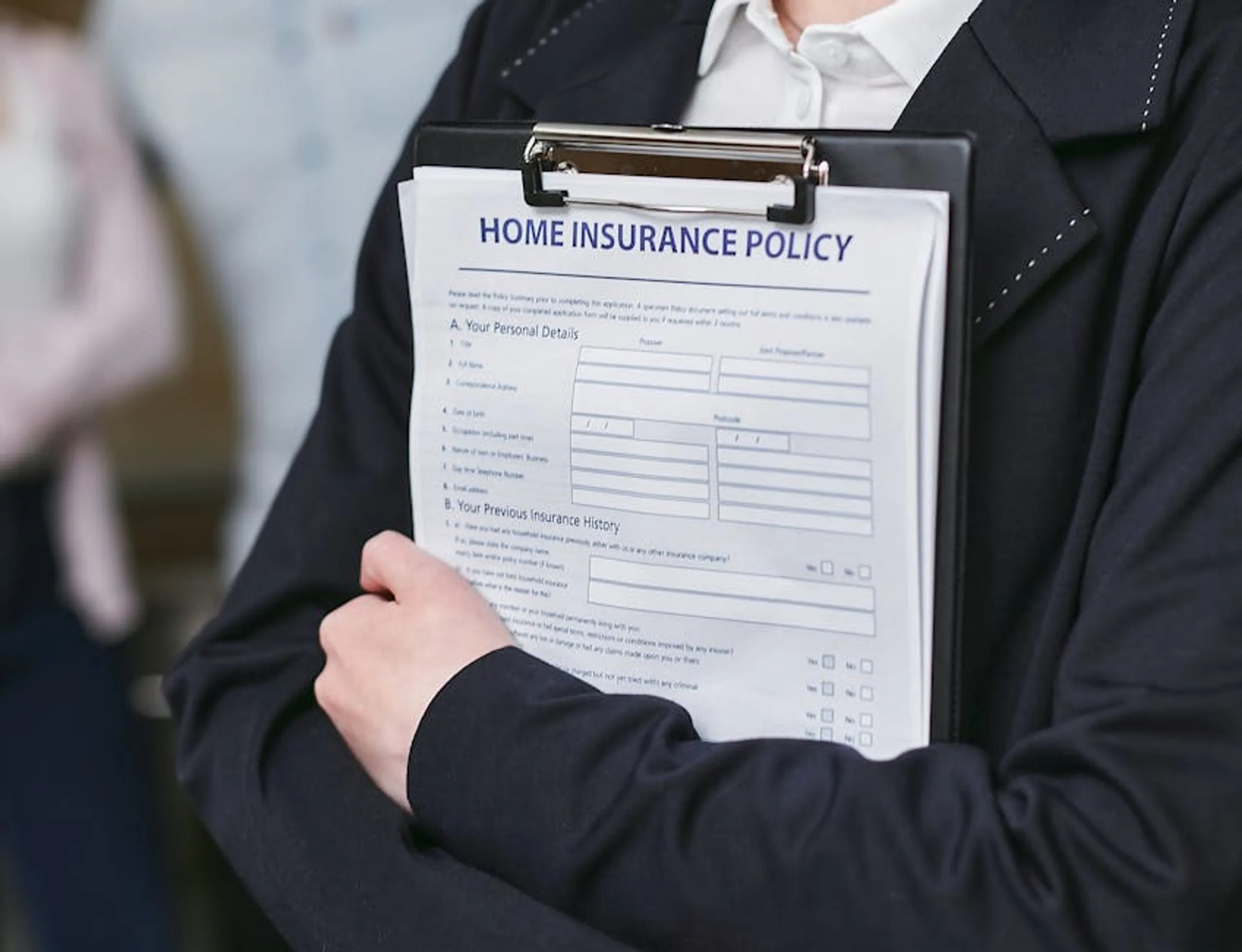 Close-up of a person holding a home insurance policy on a clipboard, captured indoors. A person reviewing a travel insurance policy document, highlighting key coverage details.